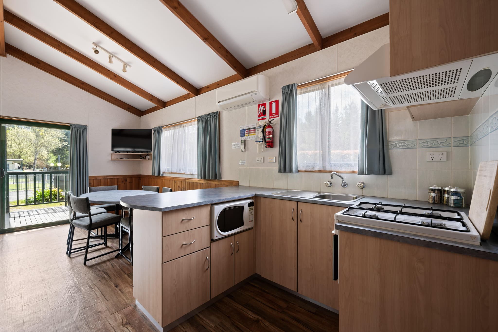 Self-contained villa kitchen with gas cooktop, microwave and dining area at Bright Accommodation Park