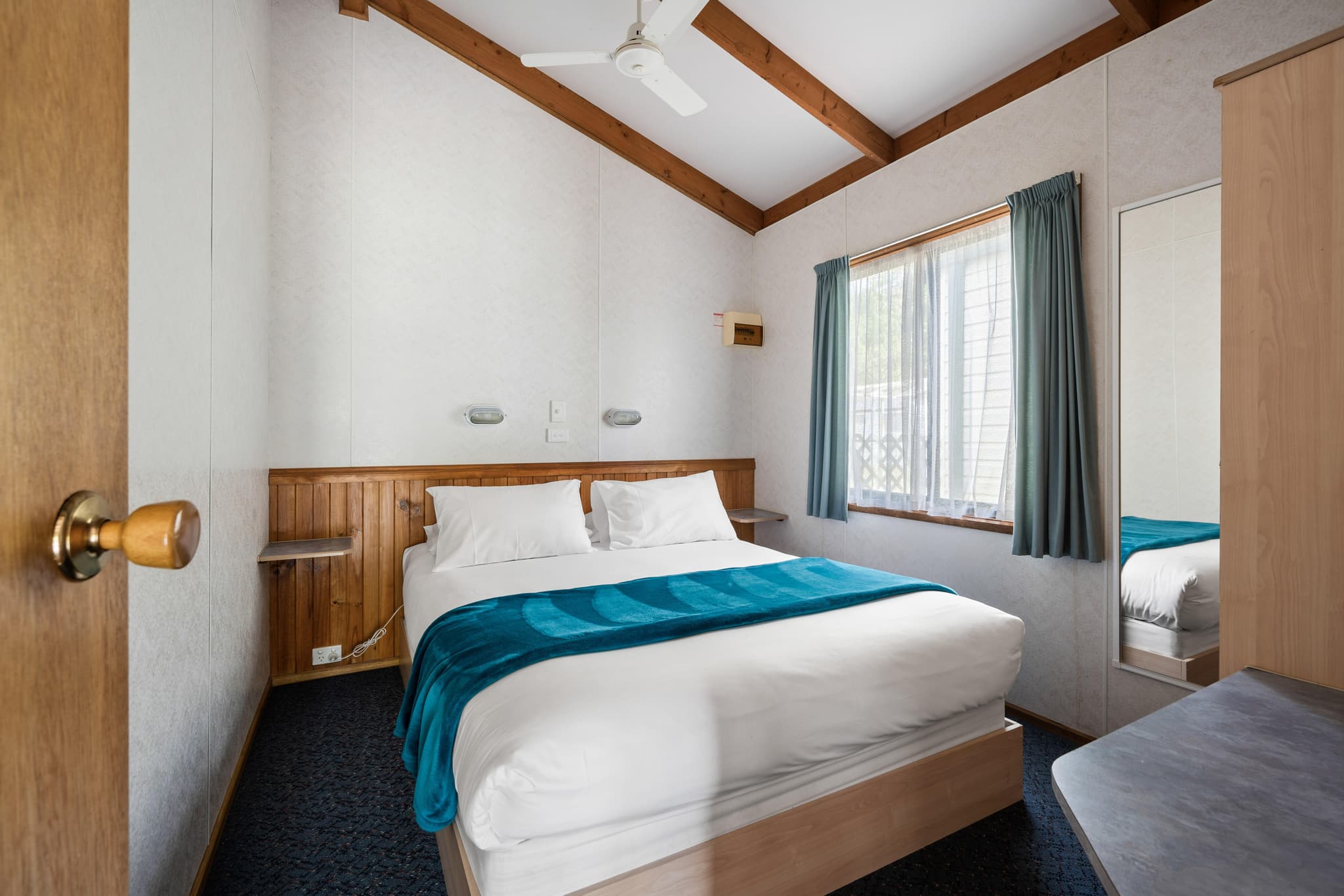 Bright Accommodation Park Supreme Villa bedroom with timber beams, queen bed, teal throw and mountain views