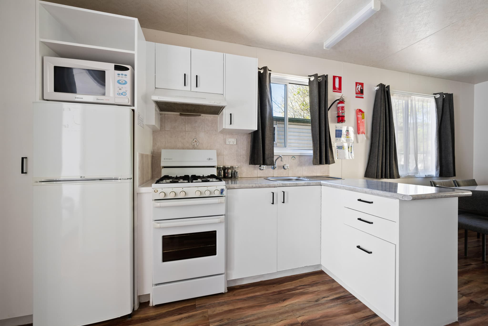 Modern kitchen in Bogong Cabin at Bright Accommodation Park with white appliances, gas stove and timber flooring