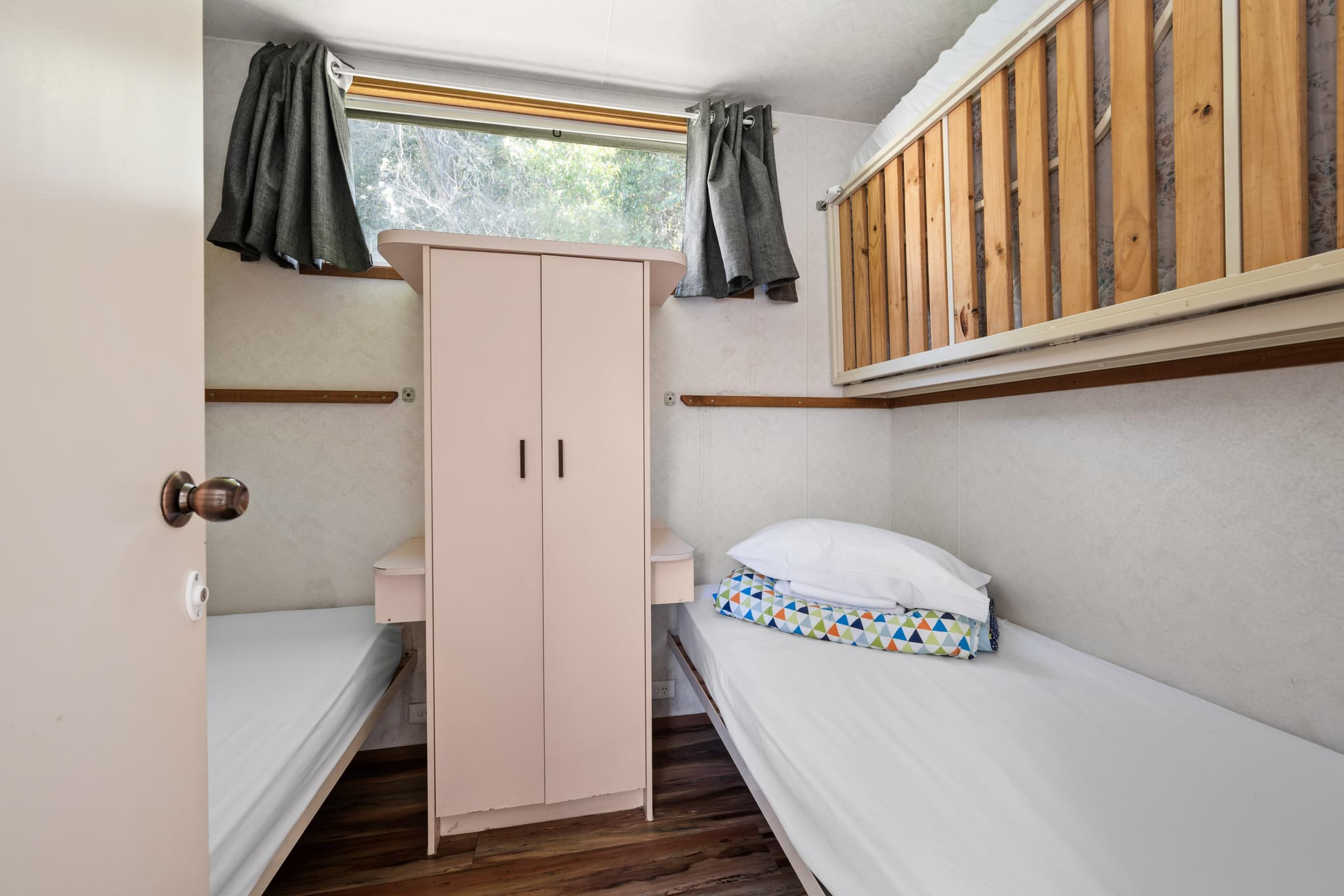 Bogong cabin bedroom at Bright Accommodation Park with bunk bed, single bed, wardrobe and natural light