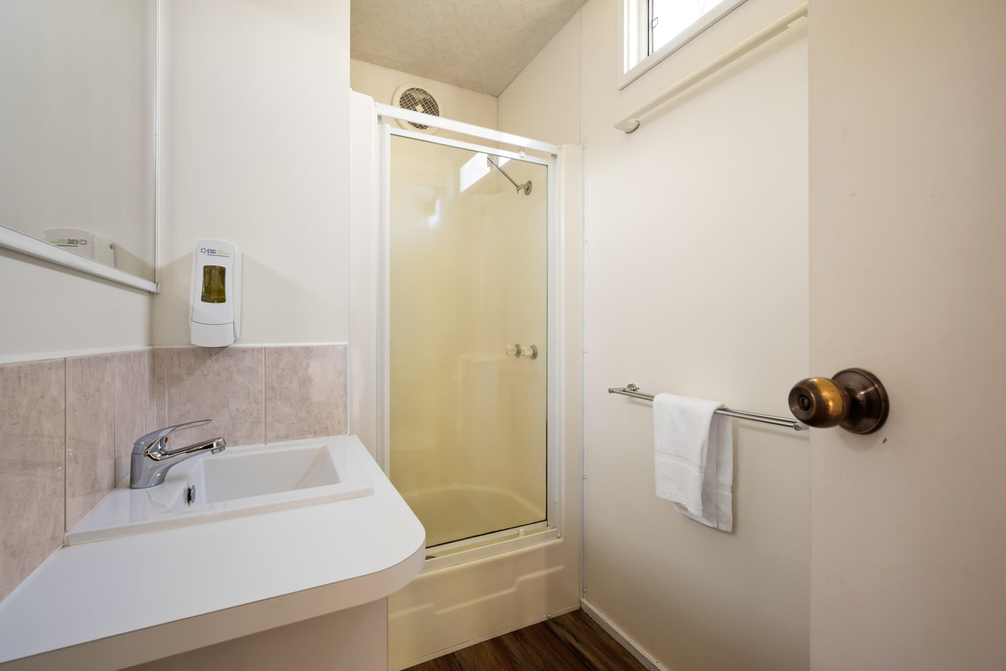 Modern bathroom in Bogong Cabin at Bright Accommodation Park with white vanity, tiled shower and timber flooring