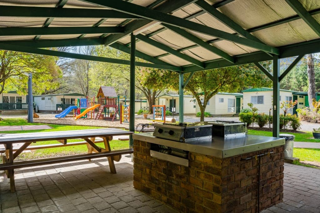 Covered BBQ area with stone facilities and playground at Bright Accommodation Park, Bright VIC